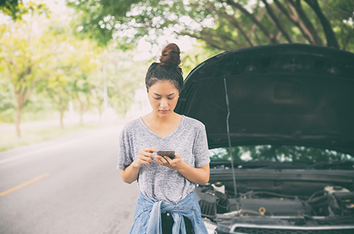 car broken down on side of road, young Asian woman using cellphone, emergency, emergency fund, emergency cash