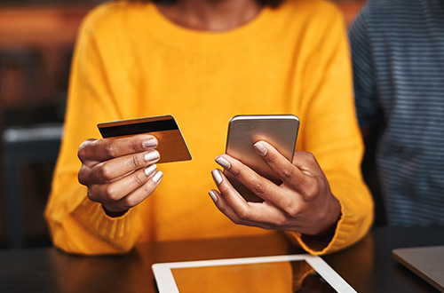 young woman in yellow sweater holding credit card and smartphone, credit card, online shopping, online credit card payment, bill pay, building credit, credit utilization ratio