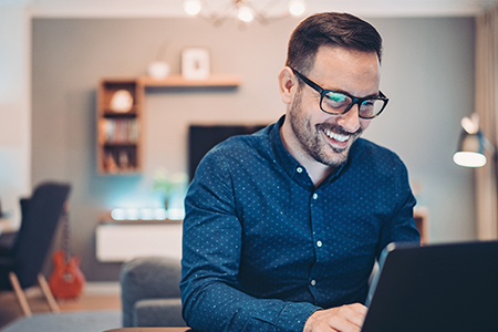 Smiling man typing on laptop