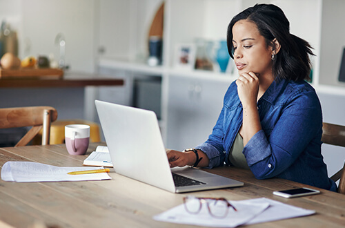 woman at kitchen table in front of laptop