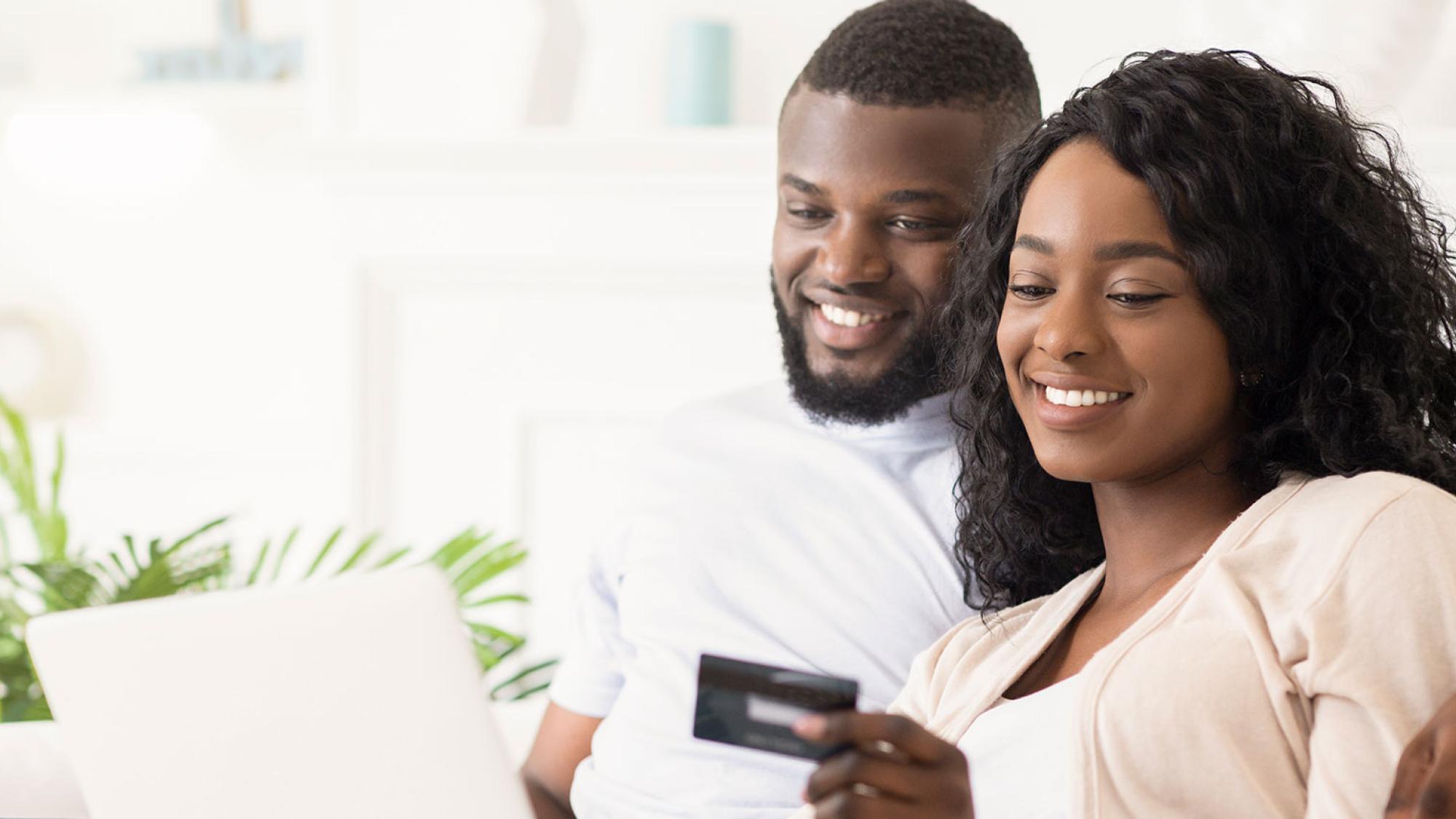 Young couple looking at credit card and smiling