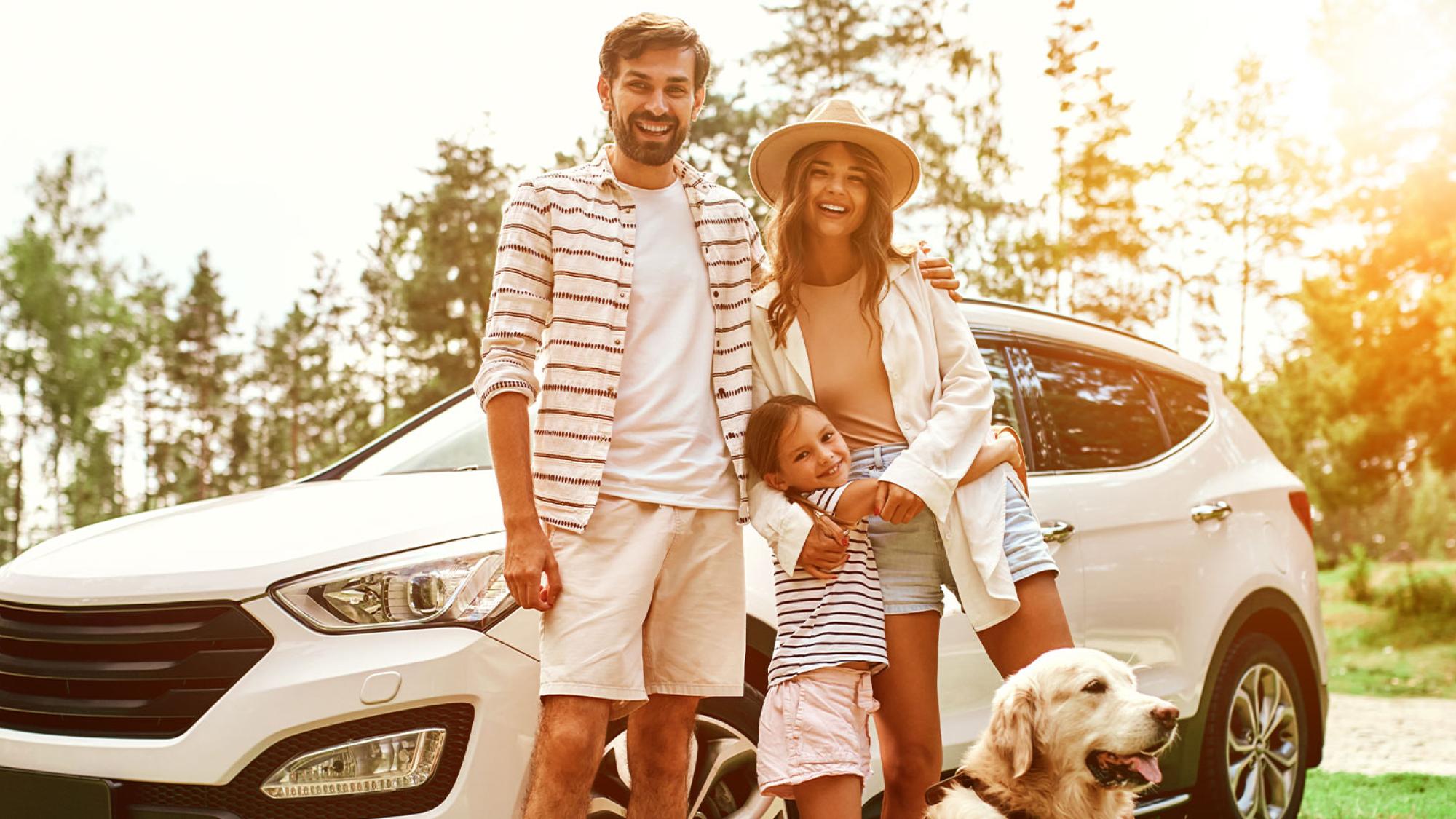 Happy family standing in front of car