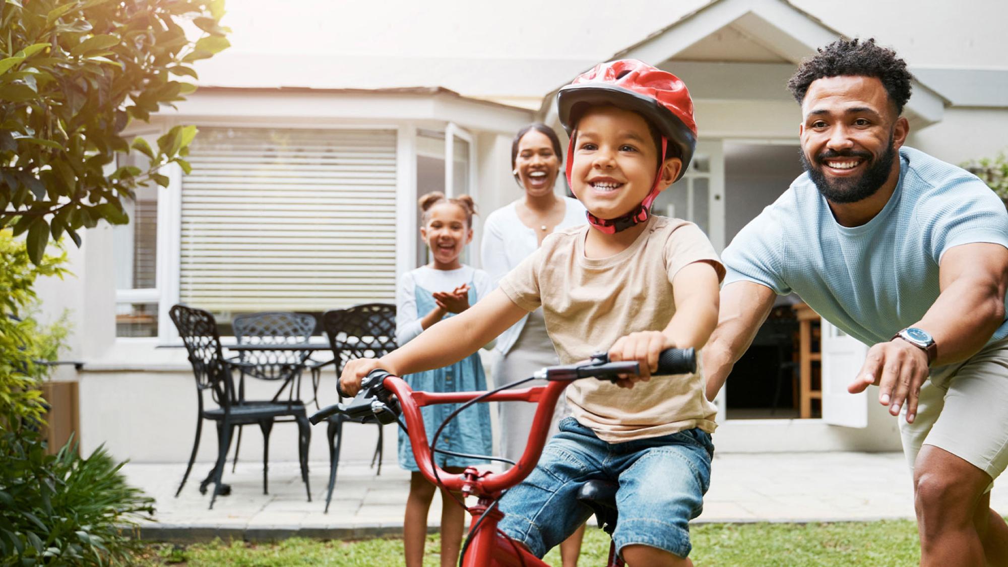 Father pushing child on bike