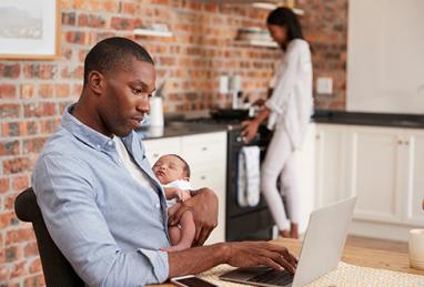 dad holding baby while on computer learning about digital banking transfer limits