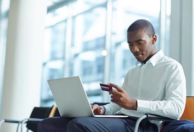 man sitting in front of laptop with credit card