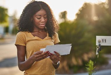 woman at mailbox receiving a fake check scam