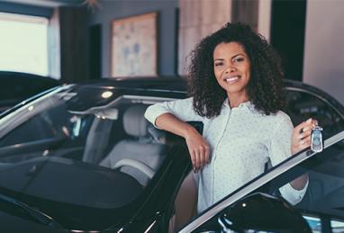 smiling woman next to car, refinance auto loan