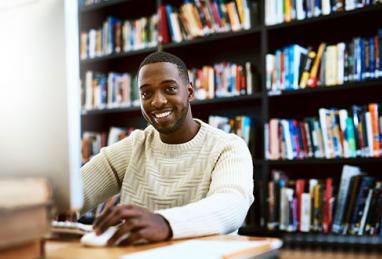 man at library sitting in front of laptop