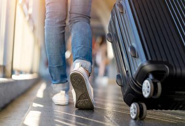 person rolling suitcase, luggage, airport, bus station, travel, vacation, road trip, summer, travel scams, how to avoid travel scams 