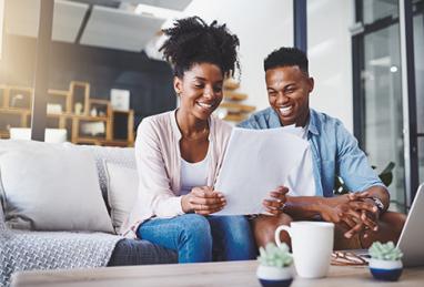 young black couple smiling at each other and managing home finances, budgeting, savings, bills, saving for a down payment