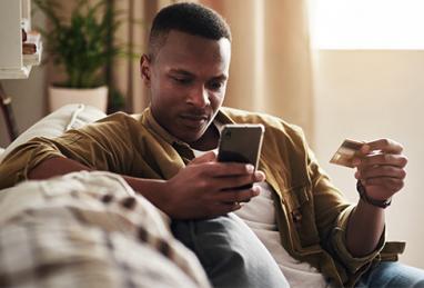 handsome black man holding credit card and smartphone, entering credit card information, online shopping, digital banking, online account, card fraud, preventing card fraud