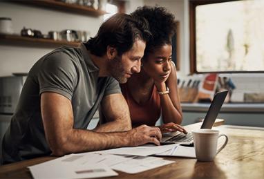 mixed race couple using laptop and reviewing their finances, rebuilding budget, financial review, financial setback