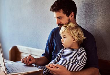 father holding young son and using laptop, digital banking, personal finances, protecting your account, quarantine, coronavirus, COVID-19