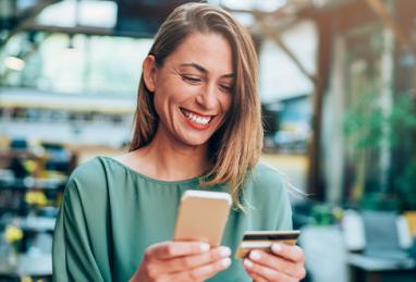 young woman sitting outside holding credit card and smartphone, credit card, digital banking, checking credit score 