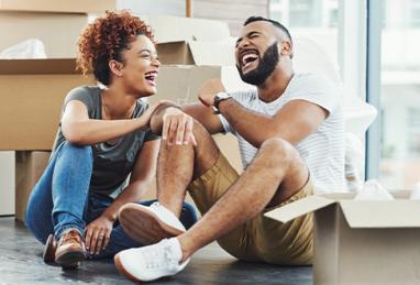 happy young couple smiling and laughing on the floor of new home surrounded by moving boxes, new home, buying a home, home buying, moving, first home 