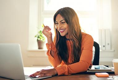 young black woman smiling and working on laptop computer, working, paycheck, direct deposit, setting up direct deposit