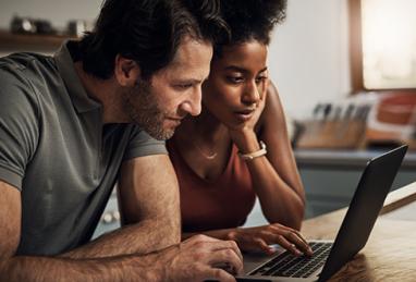 mixed race couple using laptop in the kitchen, reviewing their finances, need cash now