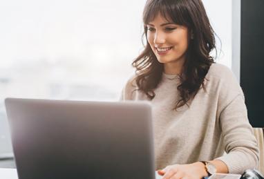 young white woman smiling using laptop, online banking, digital banking, savings account, emergency fund