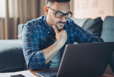  white man wearing glasses using computer, job searching, job loss, income loss, financial stress 