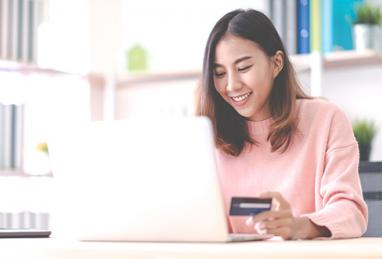 young Asian woman college student using laptop and holding credit card