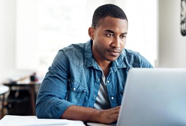 black man sitting at desk using laptop, online security, fraud prevention