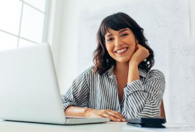 young woman sitting at desk using laptop, checking her credit, credit history, credit score 