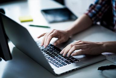 close-up of hands typing on a laptop keyboard 