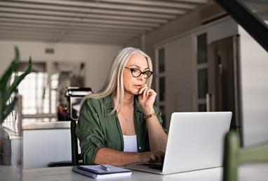 senior woman using laptop at home to review finances