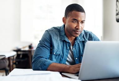 handsome young black man sitting at table using laptop, digital banking, cybersecurity 