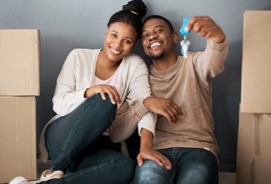 Couple sitting among boxes holding up their house key