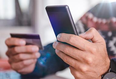 man in sweater holding credit card and smartphone, credit card, online shopping, holiday shopping, holiday scams 