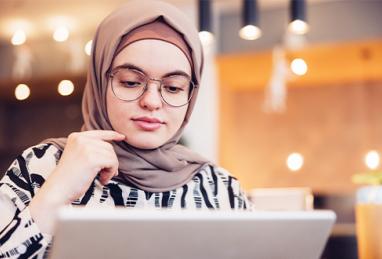 young middle eastern woman using a laptop or tablet while sitting in a café 