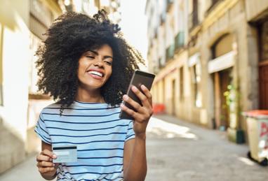 beautiful, young African-American woman standing on the street and shopping online