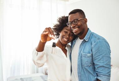 Happy African-American couple holding keys to new home 