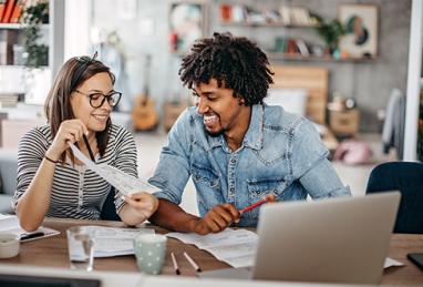 modern married multi-ethnic young couple calculating financial bills at home 