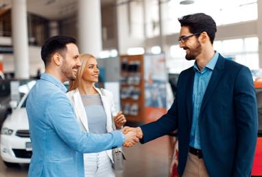 young couple shaking hands after successful car buying 