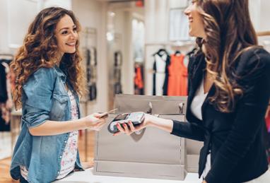 Young woman giving her credit card for a contactless payment in the fashion store