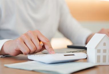 Person typing on calculator, calculating expenses for home loan, mortgage payment