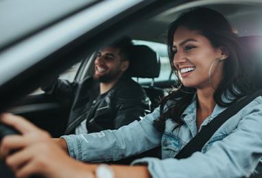 happy young couple traveling by car, woman driving and smiling, man smiling in car 