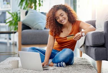 young woman using a laptop and credit card in the living room at home 