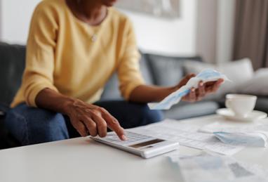 close up of a mid adult woman checking her bills at home, sitting in her living room