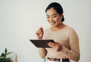 Asian woman smiling while using digital tablet