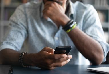 African-American man holding cell phone close-up view of hands feeling concerned 