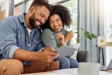 young happy mixed couple going through documents and using a digital tablet at a table together at home