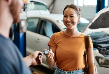 young woman handing her keys to a car repairman to have her car maintenanced