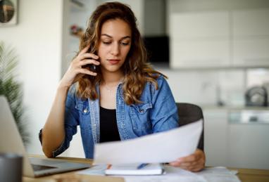 woman looking over paperwork and talking on the phone