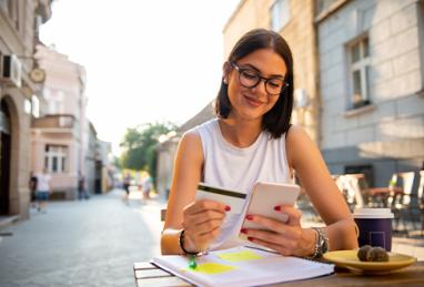 young girl sitting in a café and shopping online with her credit card