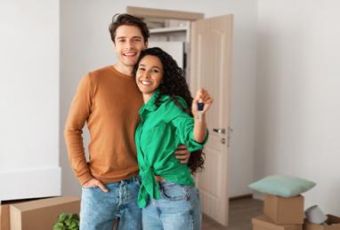 portrait of happy young couple holding keys, standing in new flat. Moving into new house. 