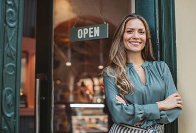 Young woman owner in front of ice cream shop in town. Small business owner. Local business. 