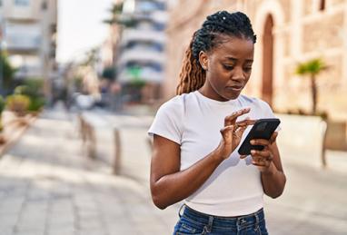 African American woman using smartphone while standing on the street